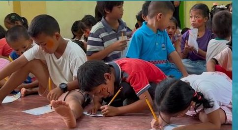 Children writing their Dear Future Me letters at the Bags of Hope area launching